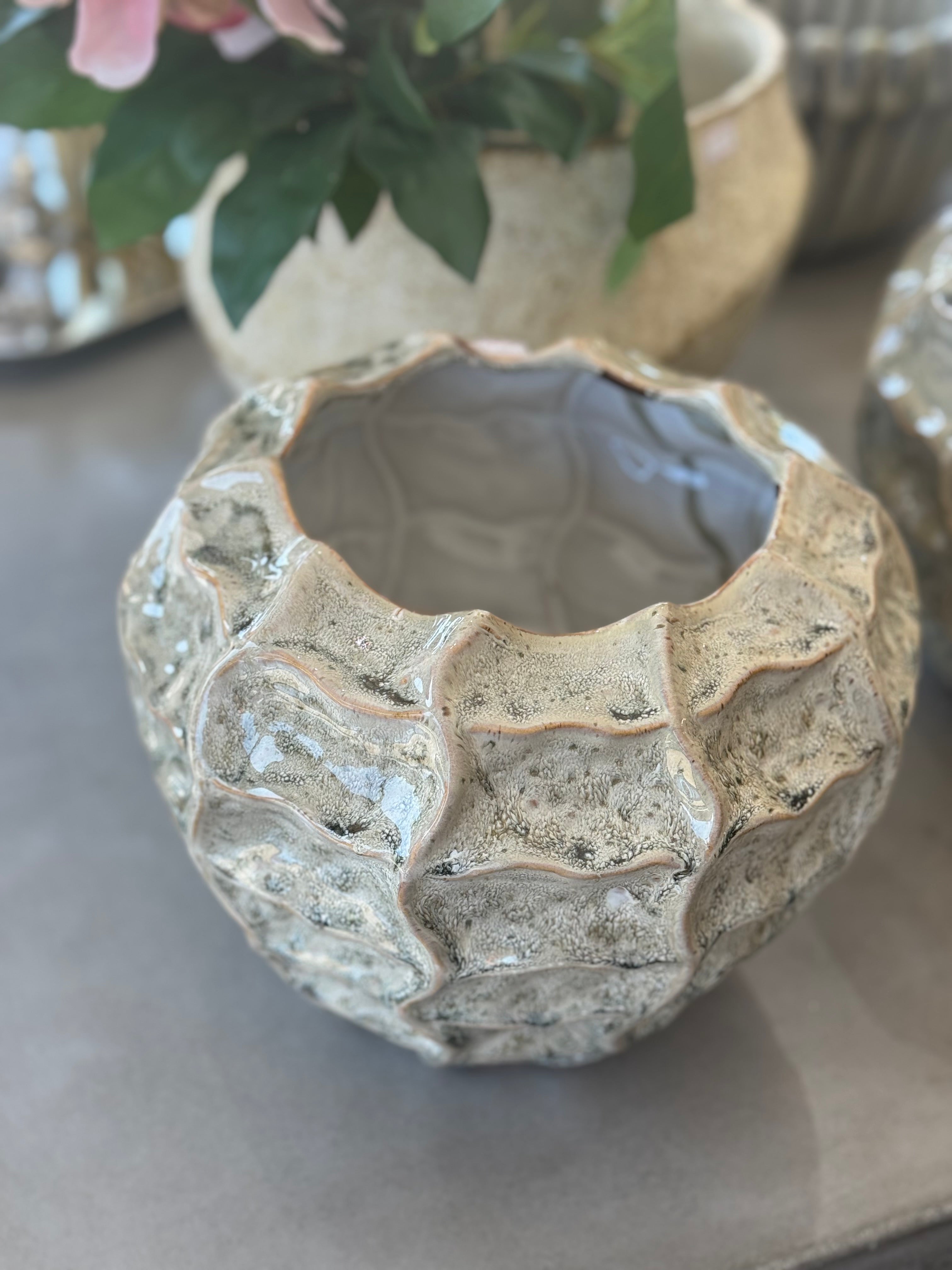 Textured ceramic pot on a neutral surface with blurred background