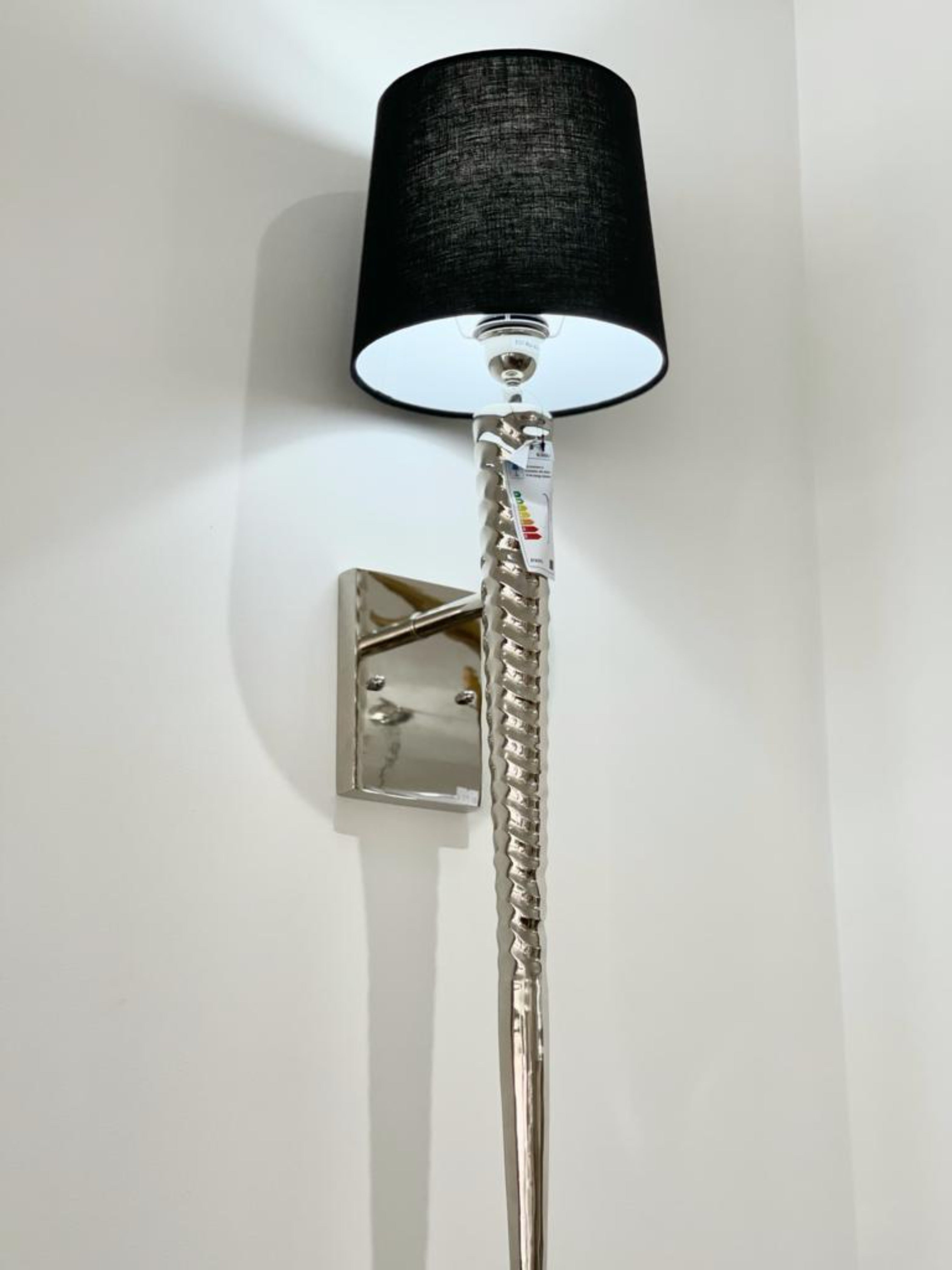 The eye catching Steel Spike Black Wall Light adds a touch of sophistication to your room. The elongated frame of the wall light is finished in polished chrome with an attractive twisted design and a black shade encasing the light. The length of this wall light makes it perfect for large walls with space to fill.
