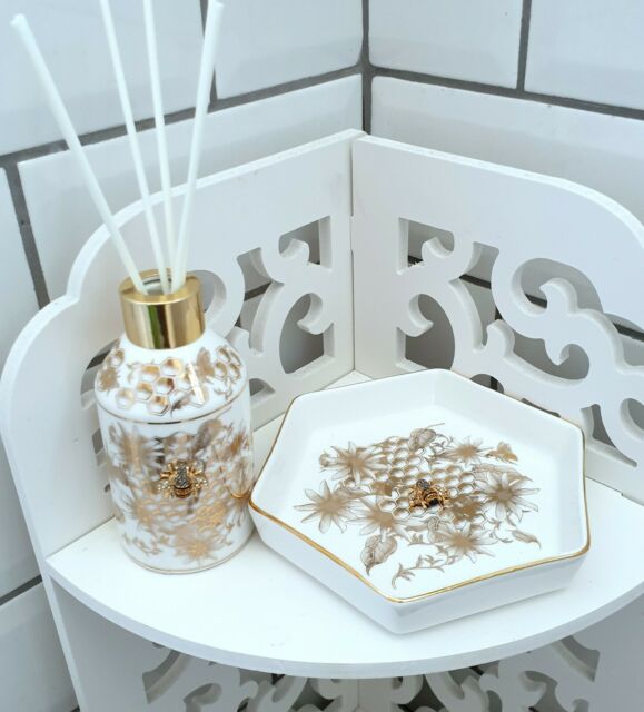 An exquisite bee, embellished with glistening jewels and set on a gold and white honeycomb background, contributes a hint of magnificence to the piece, while offering the ideal place to tuck away tiny treasures.